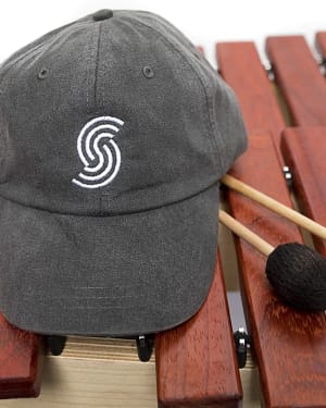 A baseball hat with a Sonaris logo and mallets sitting on top of a marimba